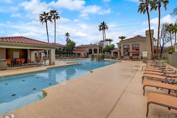 A pool surrounded by palm trees and sun loungers. at San Montego Apartments, Arizona, 85206